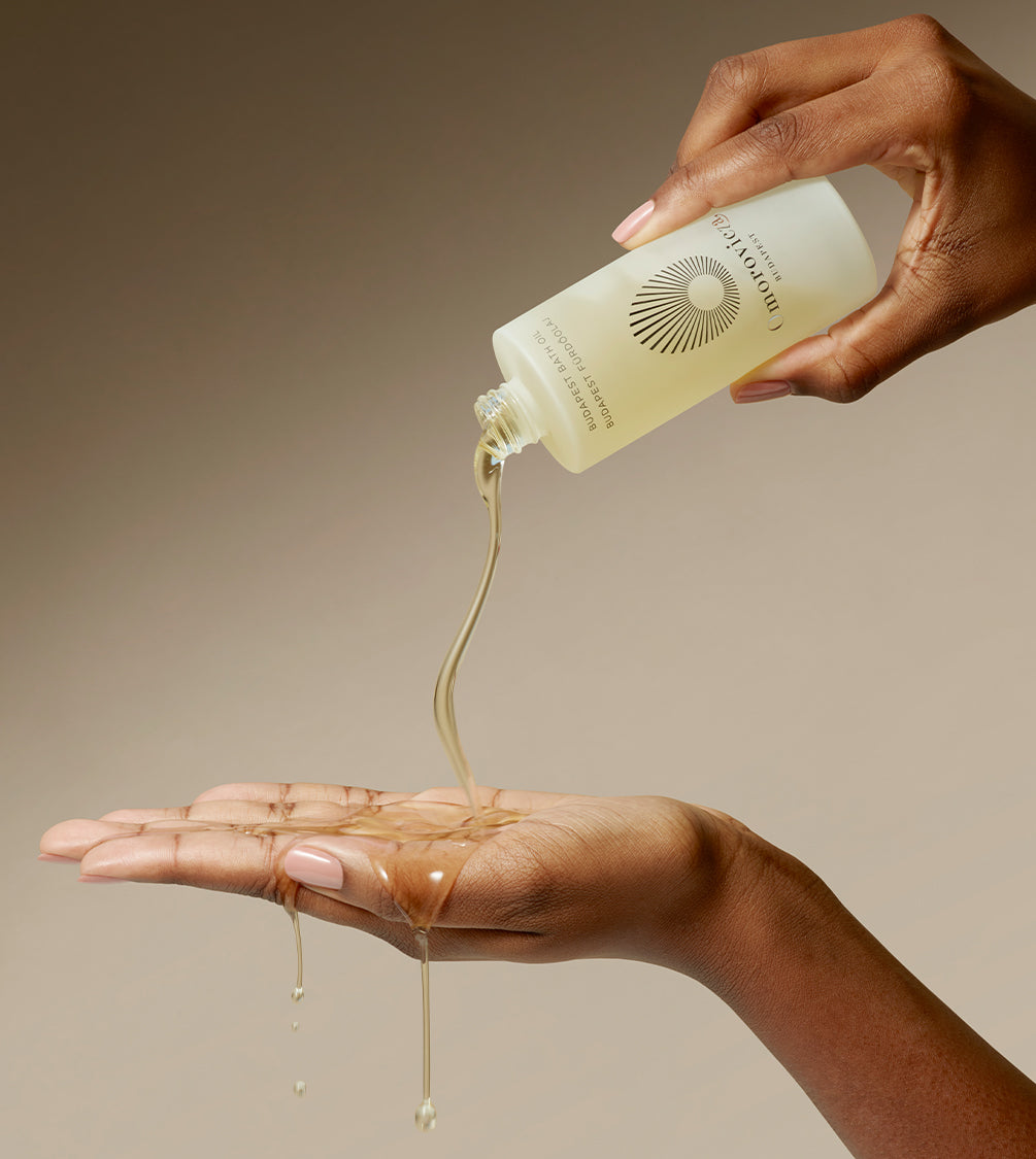 A hand is pouring Budapest Bath Oil onto another hand.