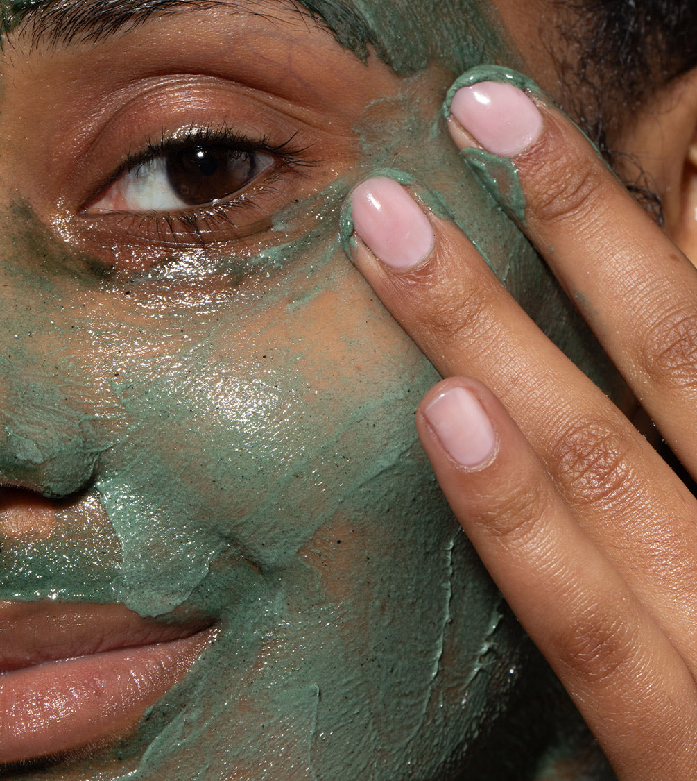 A close up of model's face with Refining Facial Polisher applied to her skin. Designed to brighten dull, lacklustre skin.