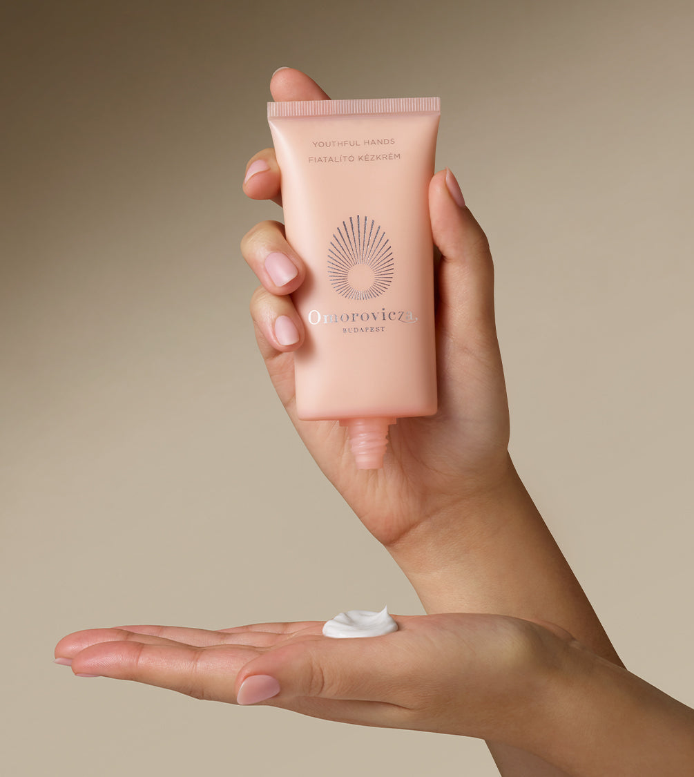 Hands are holding a tube of Youthful Hands cream.