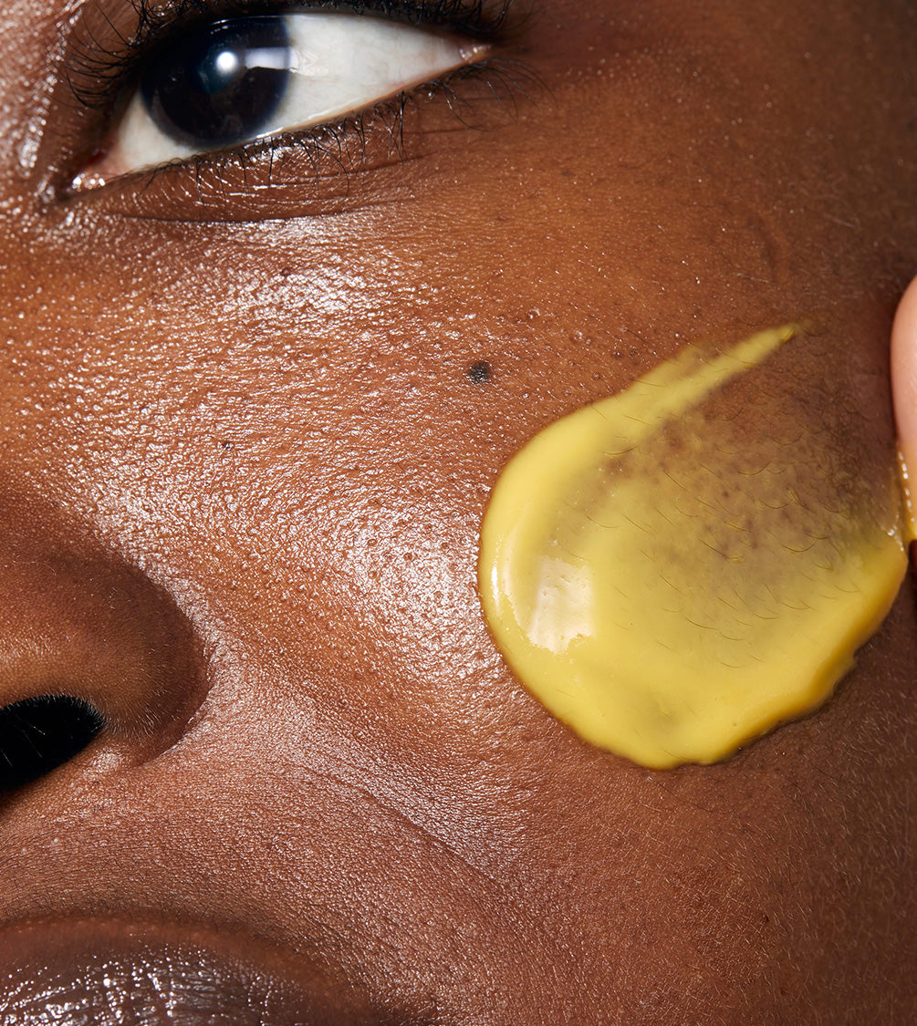 Model applying Midnight Renewal Serum to her face. The product has a light texture and a yellow colour.