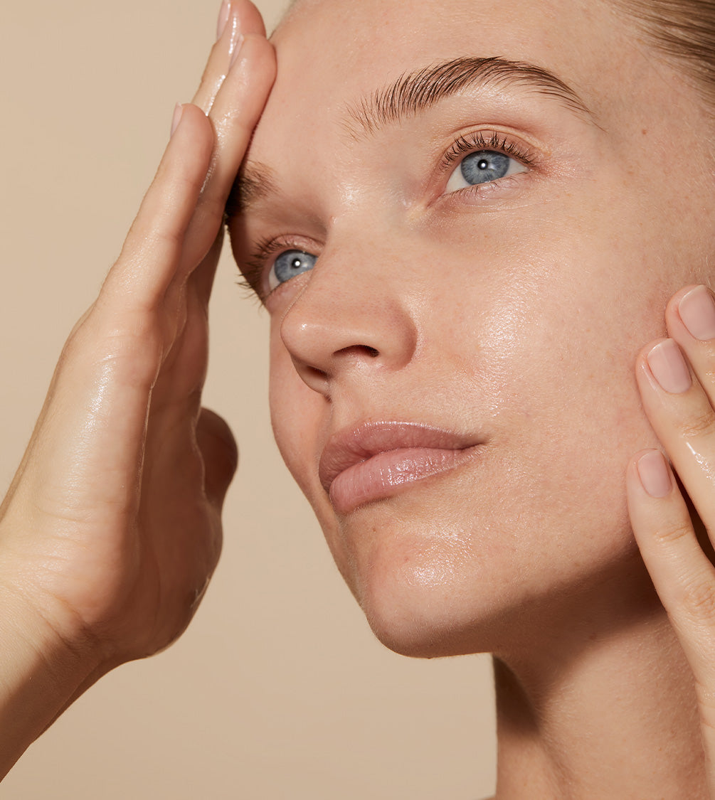 A close up of model's face with Omoressence applied to her skin.