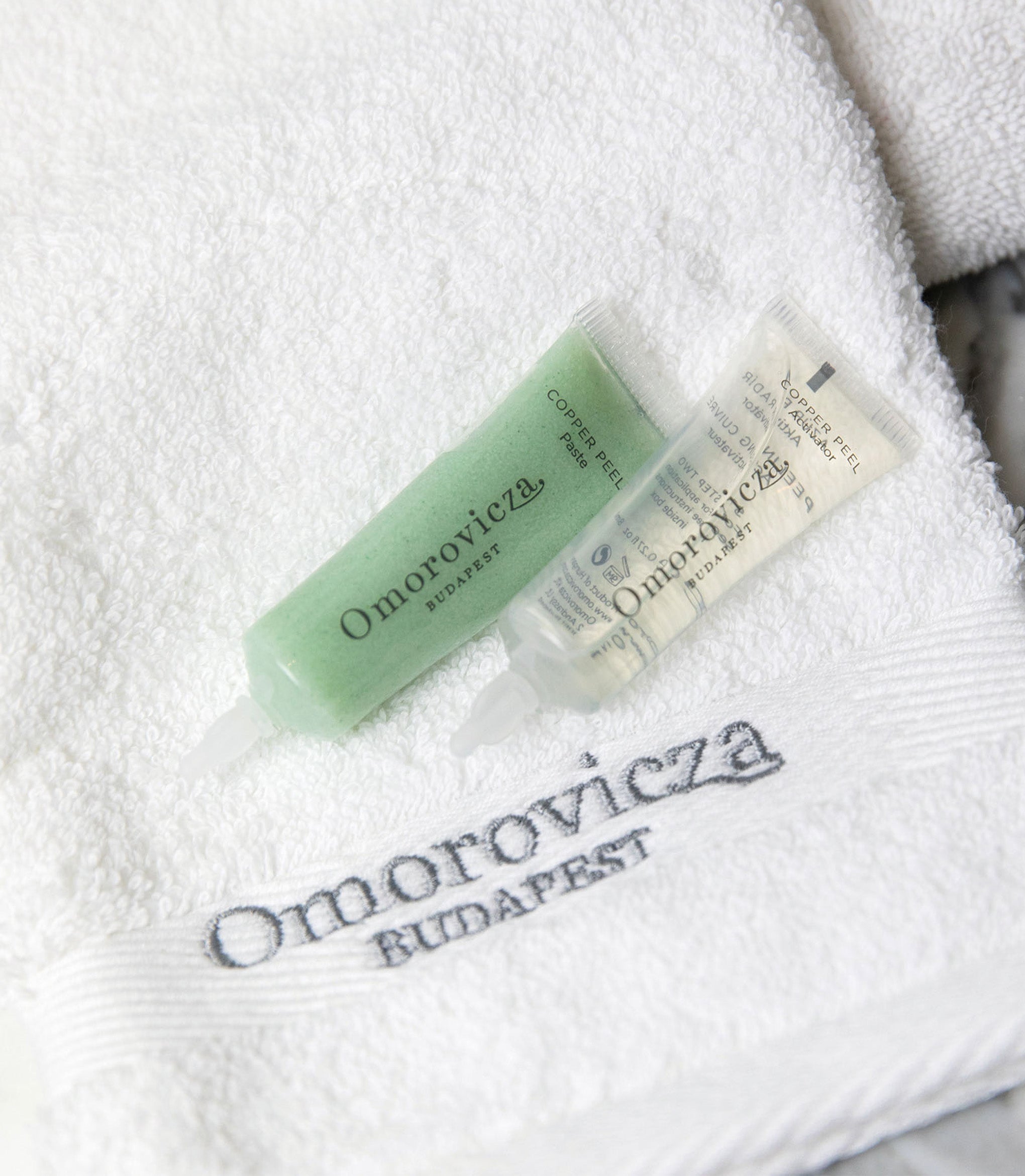 A close up of Copper peal duo placed on the towel with Omorovicza logo.