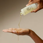 A hand is pouring Budapest Bath Oil onto another hand.