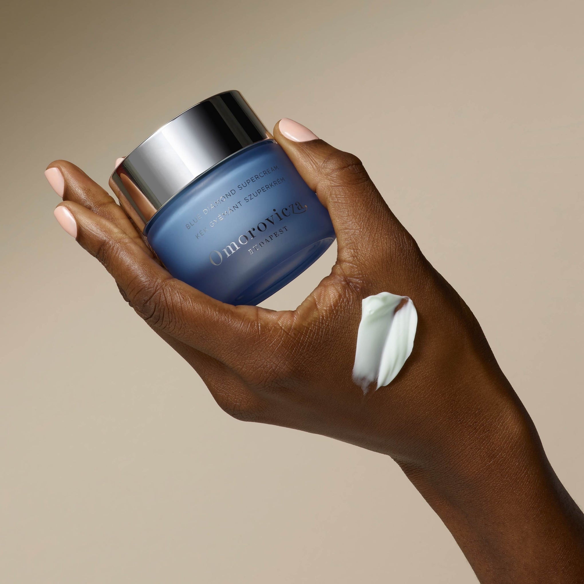 A hand is holding Blue Diamond Supercream. A swatch of the cream is applied to a hand.