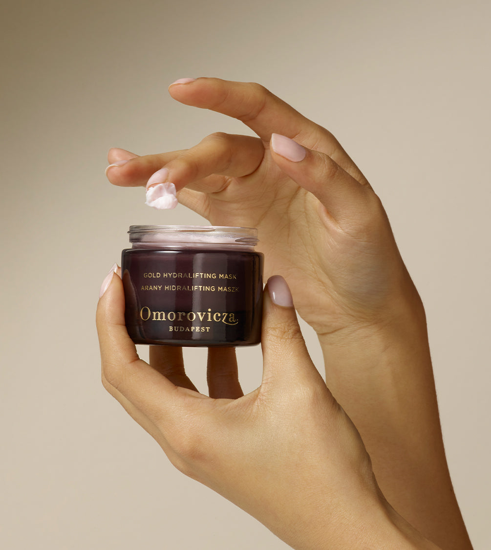 Hands are holding Gold Hydralifting Mask designed to provide an instant lift and deep hydration.