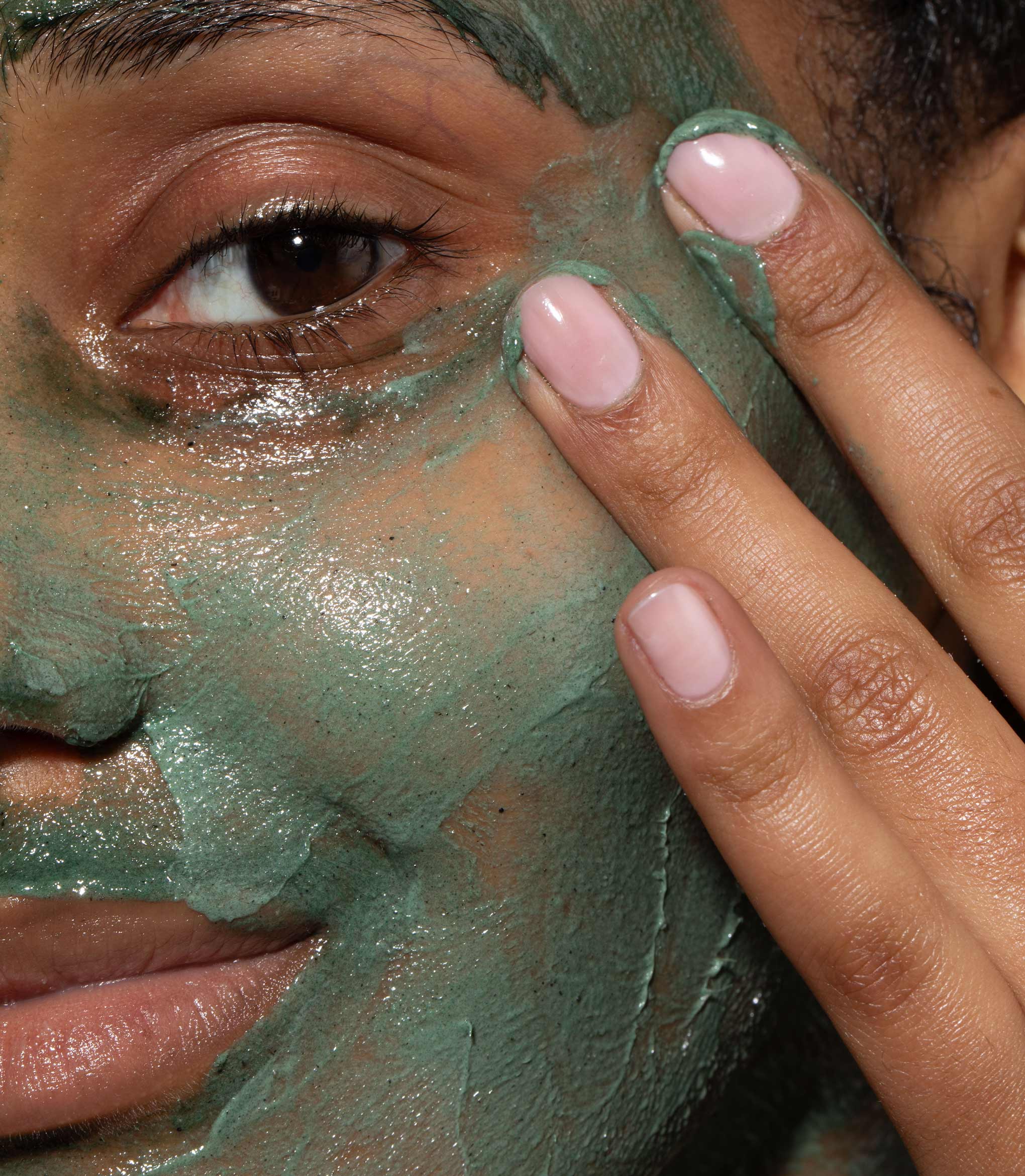 A close up of model's face with Refining Facial Polisher applied to her skin. Designed to brighten dull, lacklustre skin.