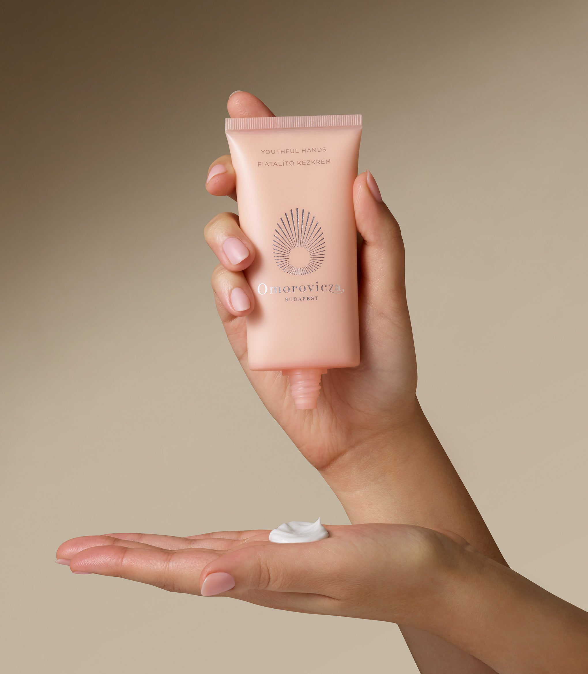 Hands are holding a tube of Youthful Hands cream.