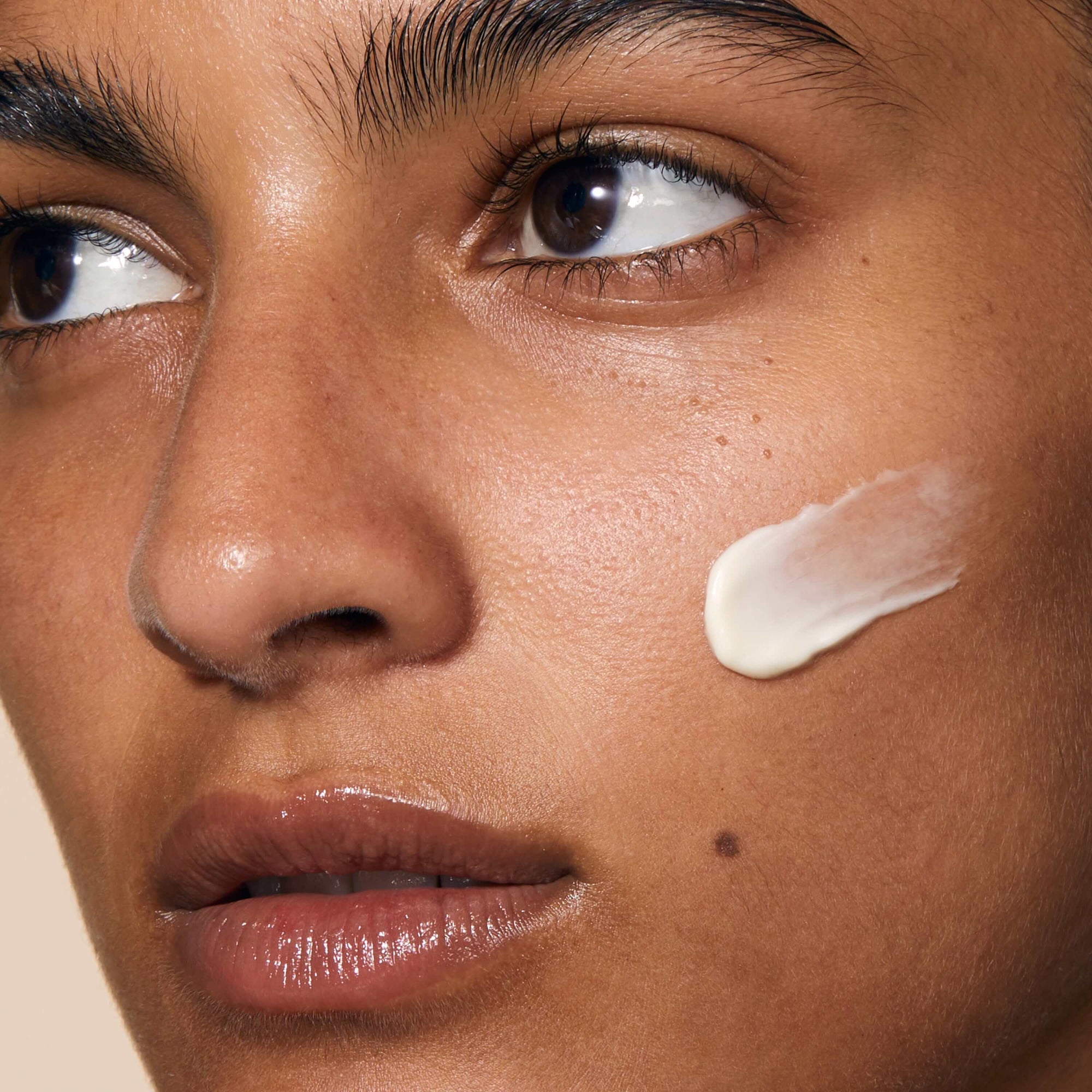 A close up of model's face showcasing application of Cushioning Day Cream