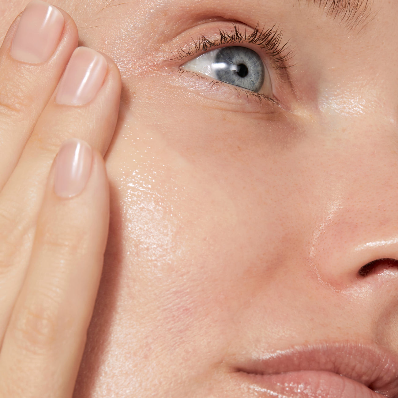 A close up of model's face with even tone applied to her skin. The skin looks glowy and smooth 
