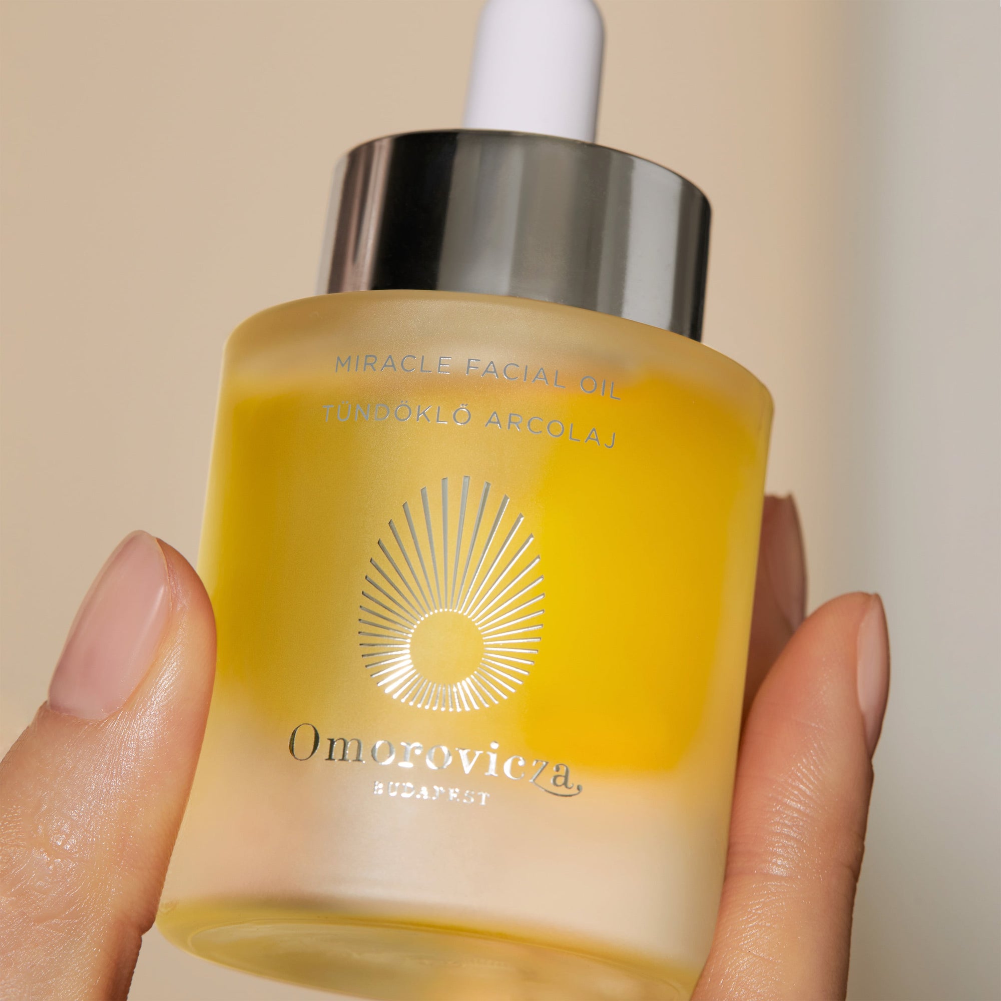 Hand holding a bottle of Omorovicza Miracle Facial Oil.